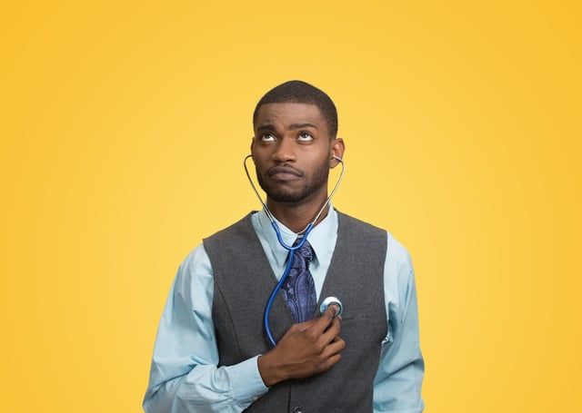 Closeup portrait executive man, business person, worker listening to his heart with stethoscope looking up isolated yellow background. Preventive medicine, financial condition concept. Face expression.jpeg
