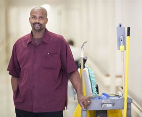Custodian standing with cleaning cart